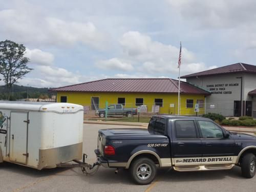 A truck with a trailer attached to it is parked in front of a building.