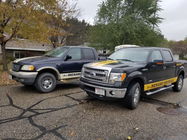 Two trucks are parked next to each other on the side of the road.