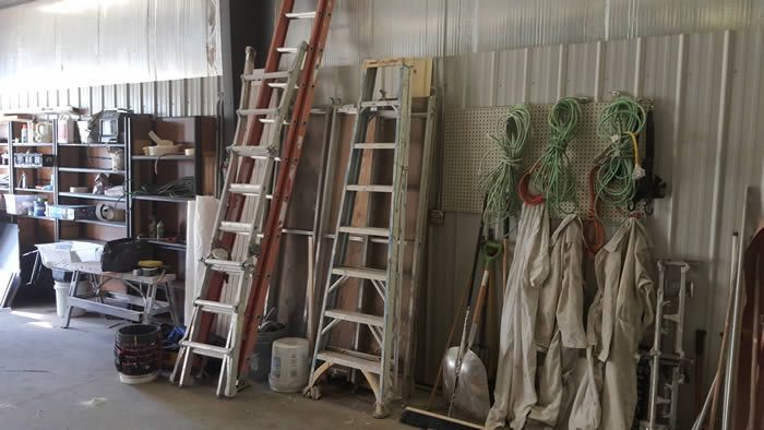 A garage filled with lots of ladders and tools.