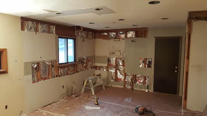 A room with a ladder and a vacuum cleaner in it is being remodeled.