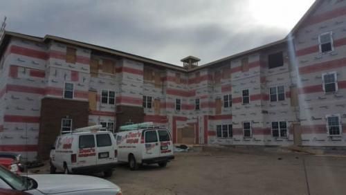 Two vans are parked in front of a large building under construction.