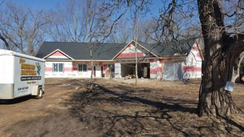 A house under construction with a trailer parked in front of it.