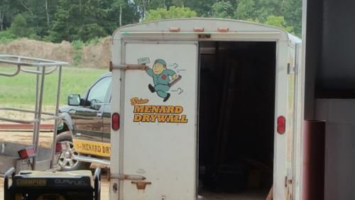 A white trailer with a picture of a man on it that says ' weyard drywall ' on it