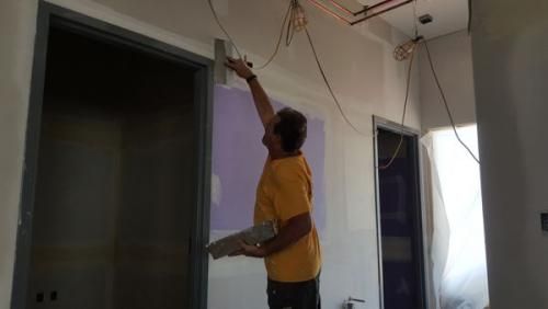 A man is painting a wall in a room.