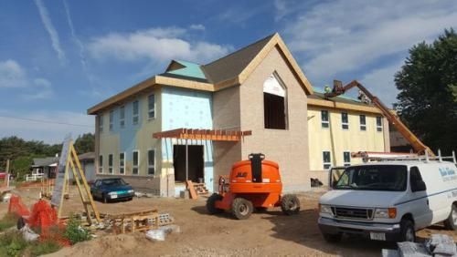 A white van is parked in front of a house under construction