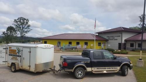 A truck with a trailer attached to it is parked in front of a building.