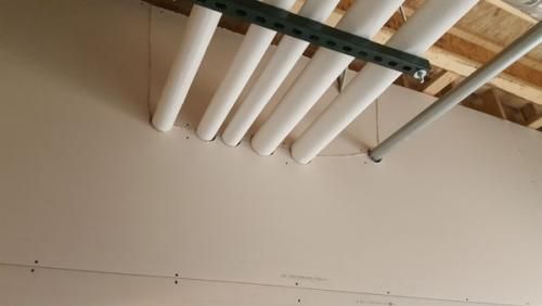 A bunch of white pipes are hanging from the ceiling of a building.