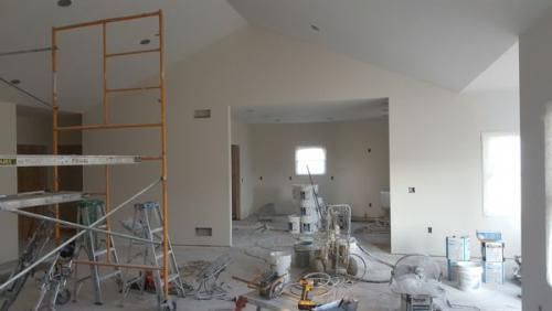 A large room with a ladder and scaffolding in it is being painted.