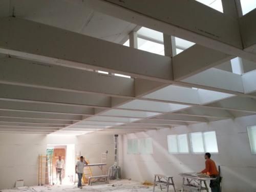 A man is standing in a room with a lot of windows.