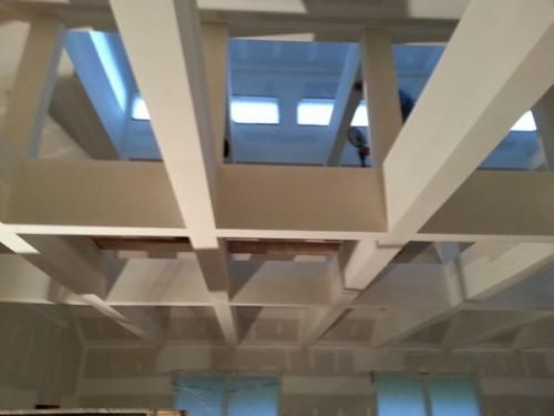 A ceiling with a lot of beams and windows