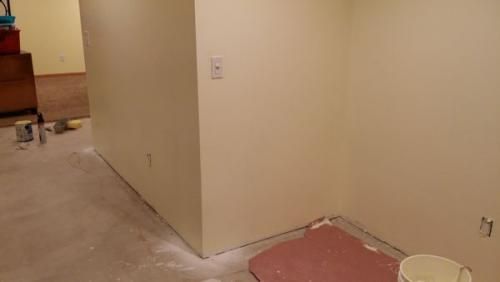 A room with white walls and a bucket of paint on the floor.