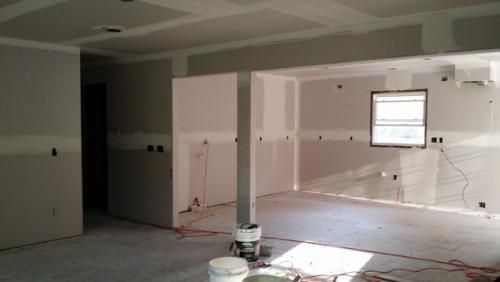 A room with a window and a bucket of paint on the floor