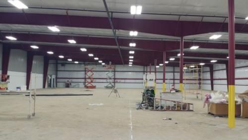 A large empty warehouse with a lot of lights on the ceiling.