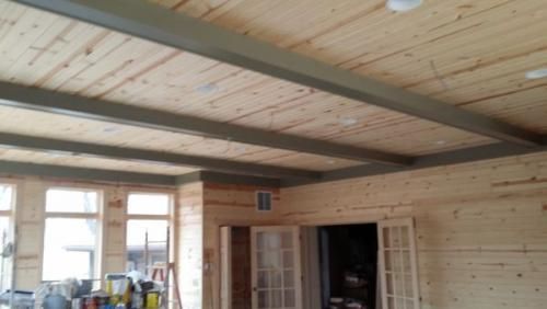 A room with a wooden ceiling and a lot of windows.