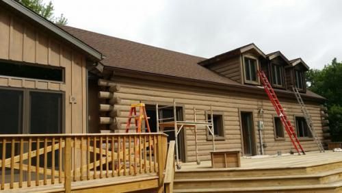 A log cabin is being remodeled with a deck and stairs.
