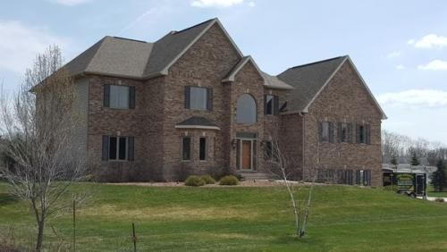A large brick house is sitting on top of a lush green hillside.