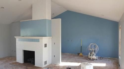 A living room with blue walls and a white fireplace