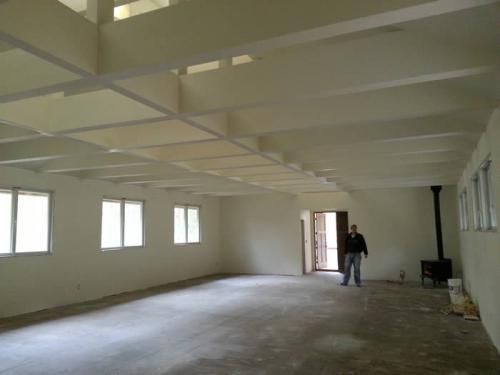 A man is standing in a large empty room with white walls.