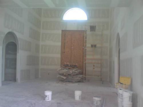 A room with drywall on the walls and a ladder in the corner.