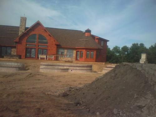 A large red brick house with a large pile of dirt in front of it.