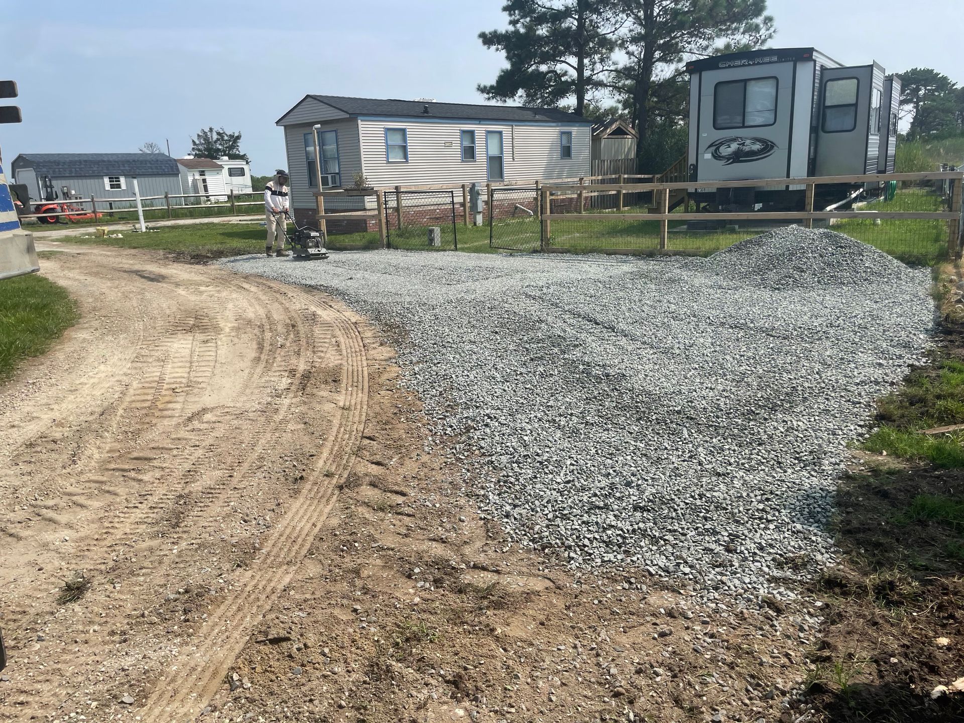 Gravel path beside a mobile home and trailer in a rural campground setting