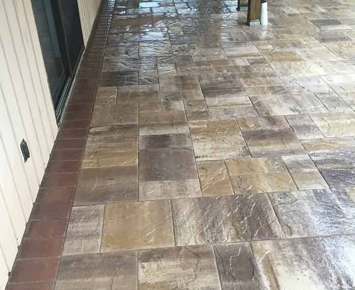 A patio with a lot of tiles on it and a brick border.