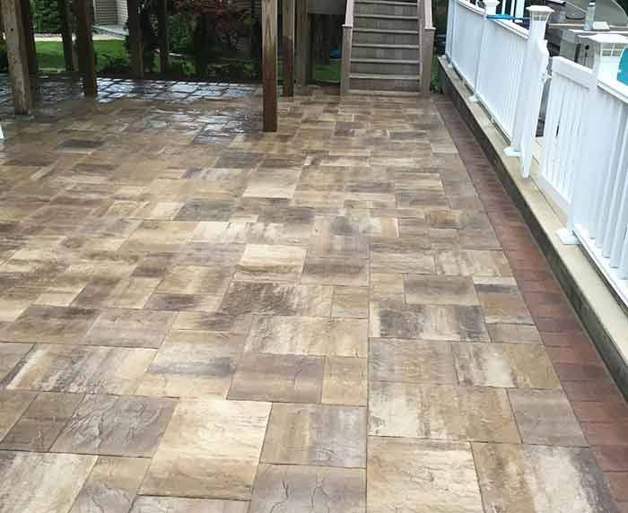 A tiled patio with stairs leading up to it and a white railing.