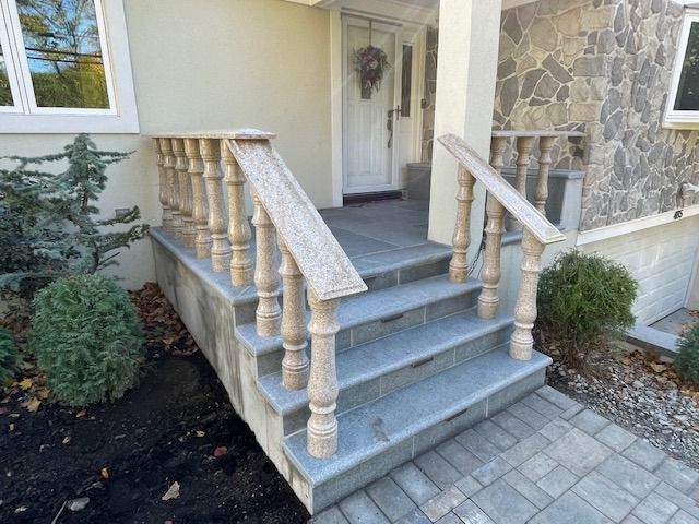The front porch of a house with stairs and a wooden railing.