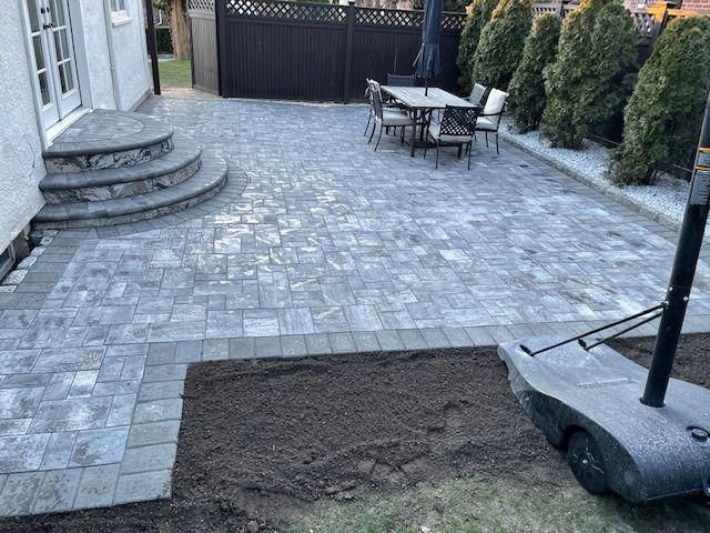 A patio with a table and chairs is being built in front of a house.