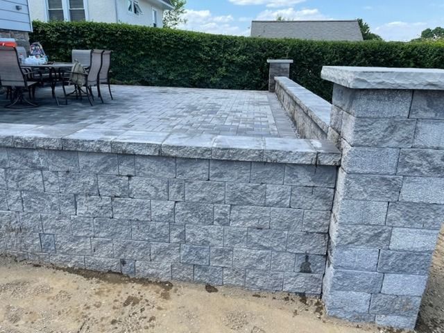 A stone wall surrounds a patio with a table and chairs.