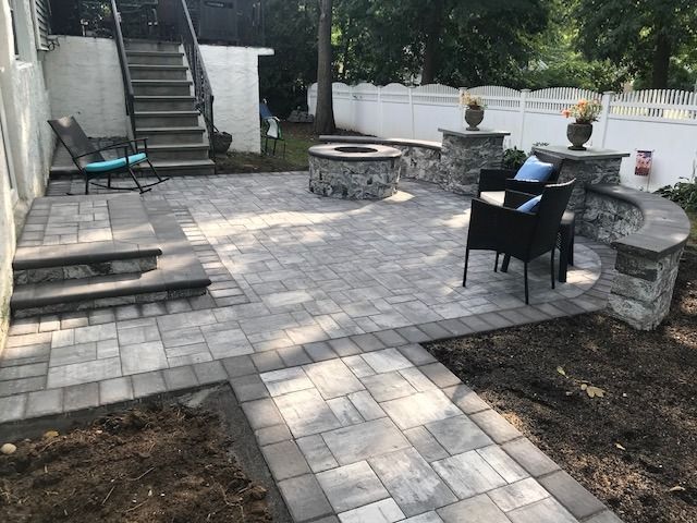 A patio with a fire pit , chairs and stairs