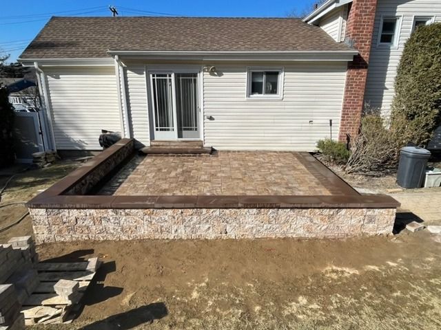 A white house with a stone wall in front of it.