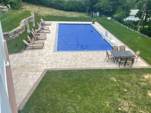 A large swimming pool with a table and chairs around it