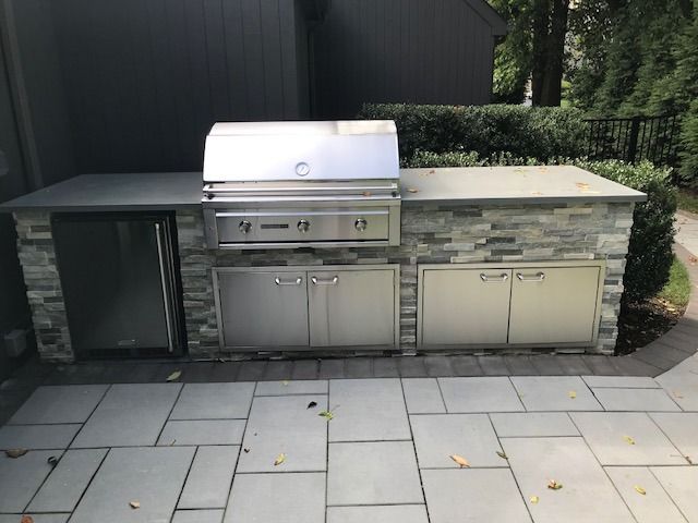 An outdoor kitchen with a grill and a refrigerator