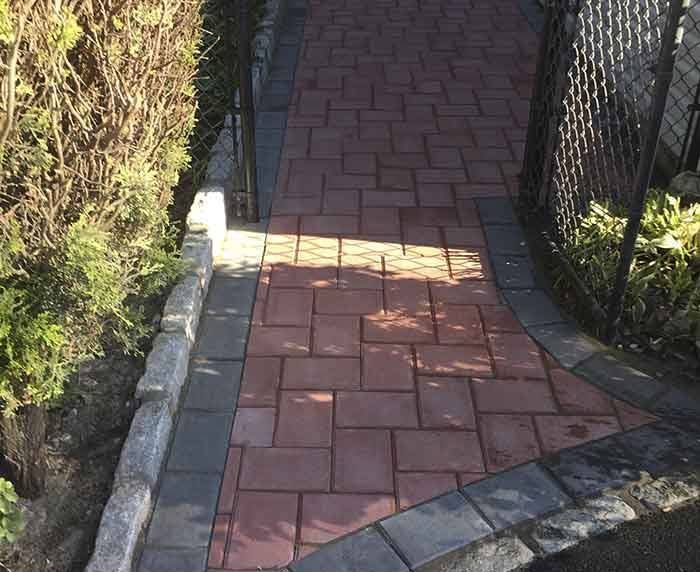 A brick walkway with a chain link fence in the background