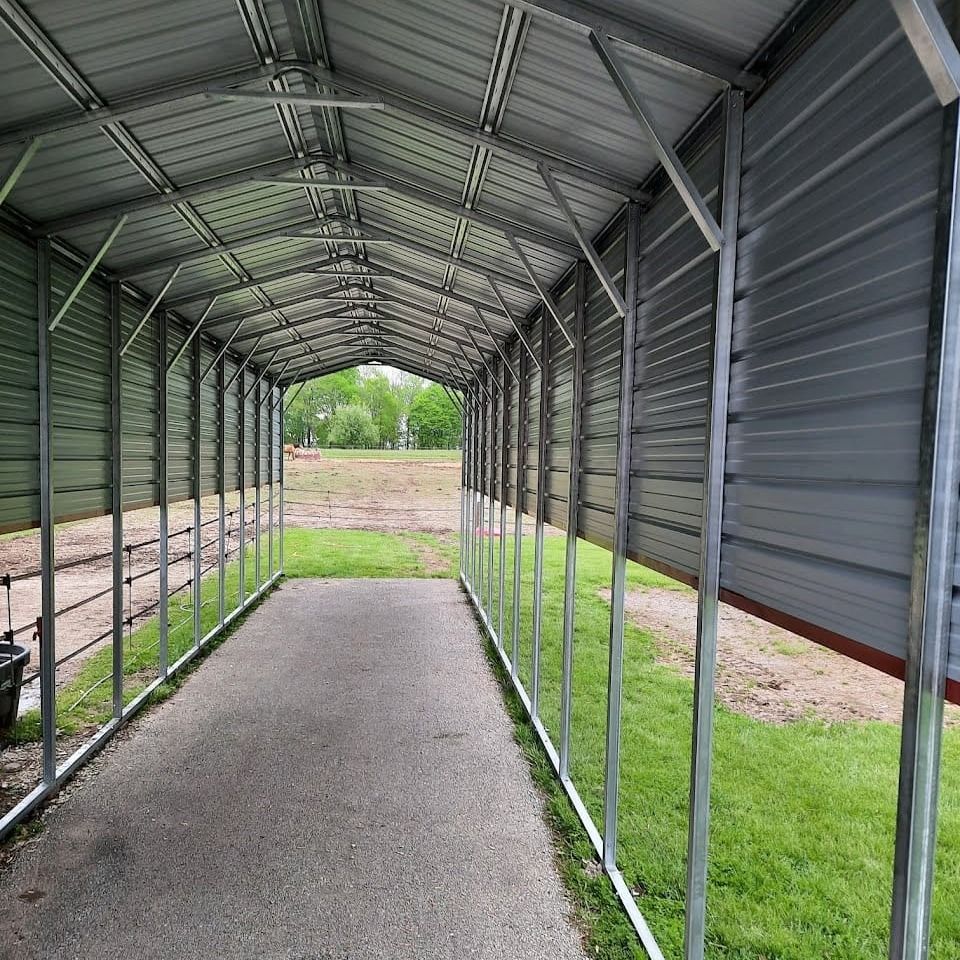 Metal carport with a gray roof and concrete pathway, on green grass.