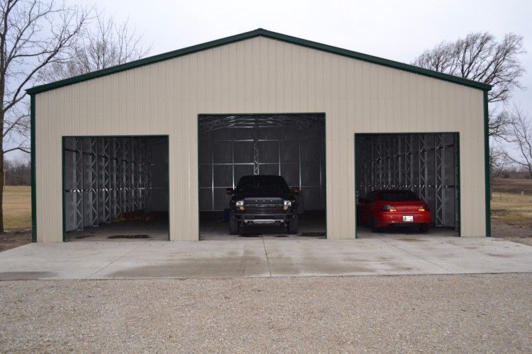 Three-bay metal garage with a black pickup truck and a red car parked inside on a concrete pad.