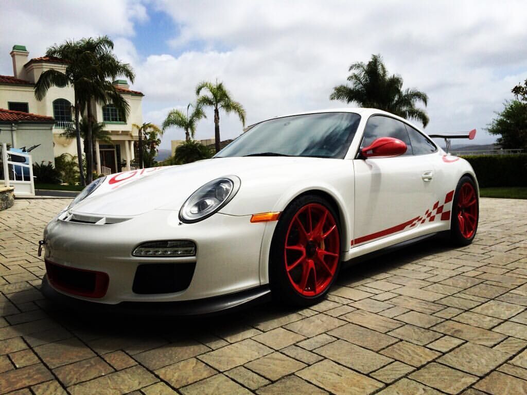 White Porsche sports car with red accents parked on brick patio.