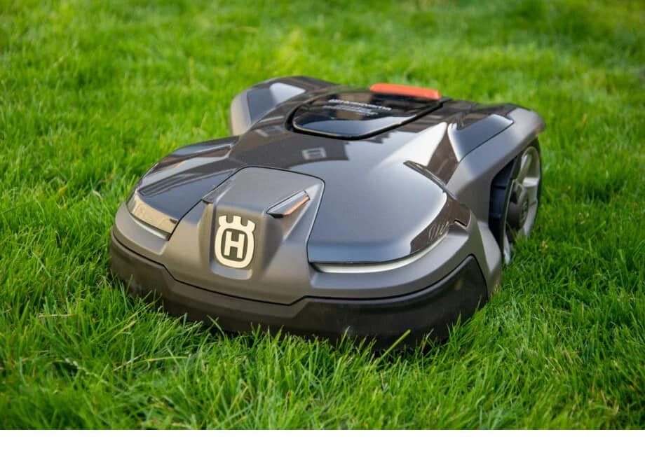 A husqvarna lawn mower is sitting on top of a lush green lawn.