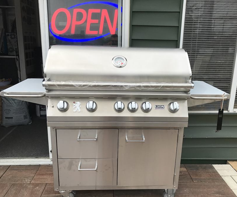 A stainless steel grill is sitting in front of an open sign