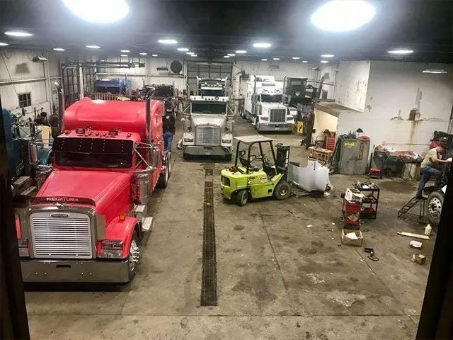 A group of semi trucks are parked in a garage.