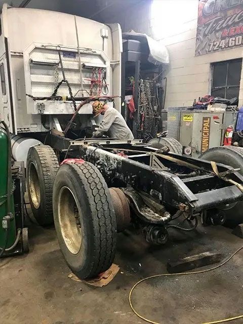 A man is working on a semi truck in a garage.