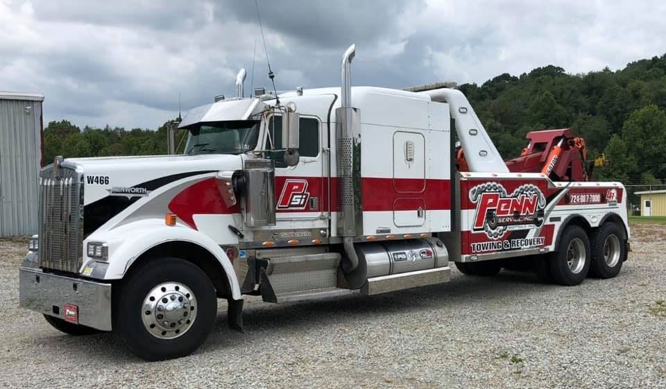 A white and red tow truck is parked in a gravel lot.