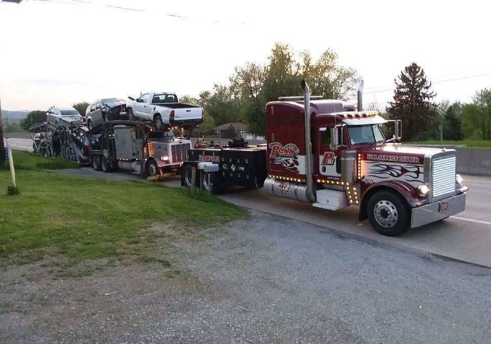 A semi truck is carrying a trailer full of cars
