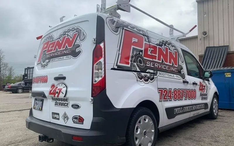 A penn service van is parked in front of a building.
