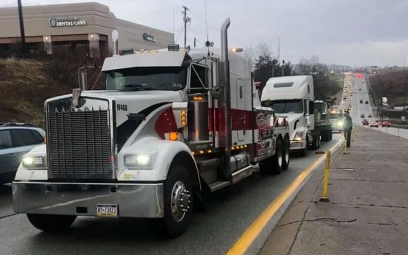 Two semi trucks are parked on the side of the road.