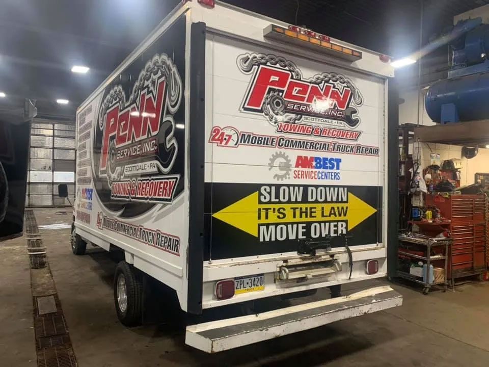 A truck is parked in a garage with a sign on the back that says `` slow down it 's the law move over ''.
