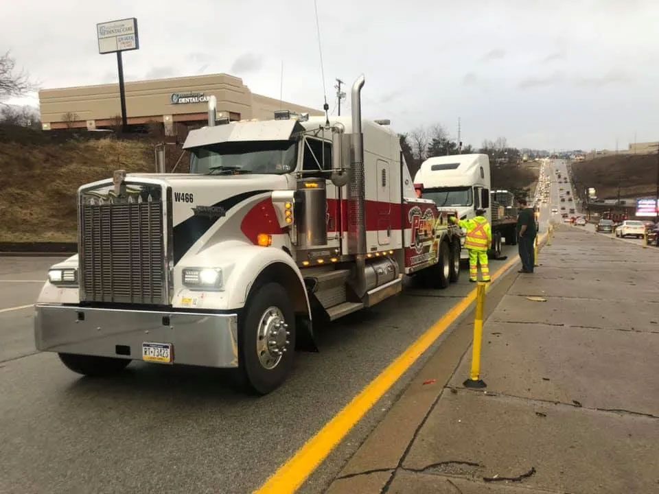 Two semi trucks are parked on the side of the road.