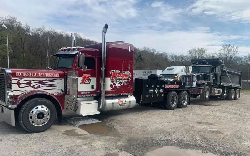 A red semi truck with a trailer attached to it is parked in a parking lot.