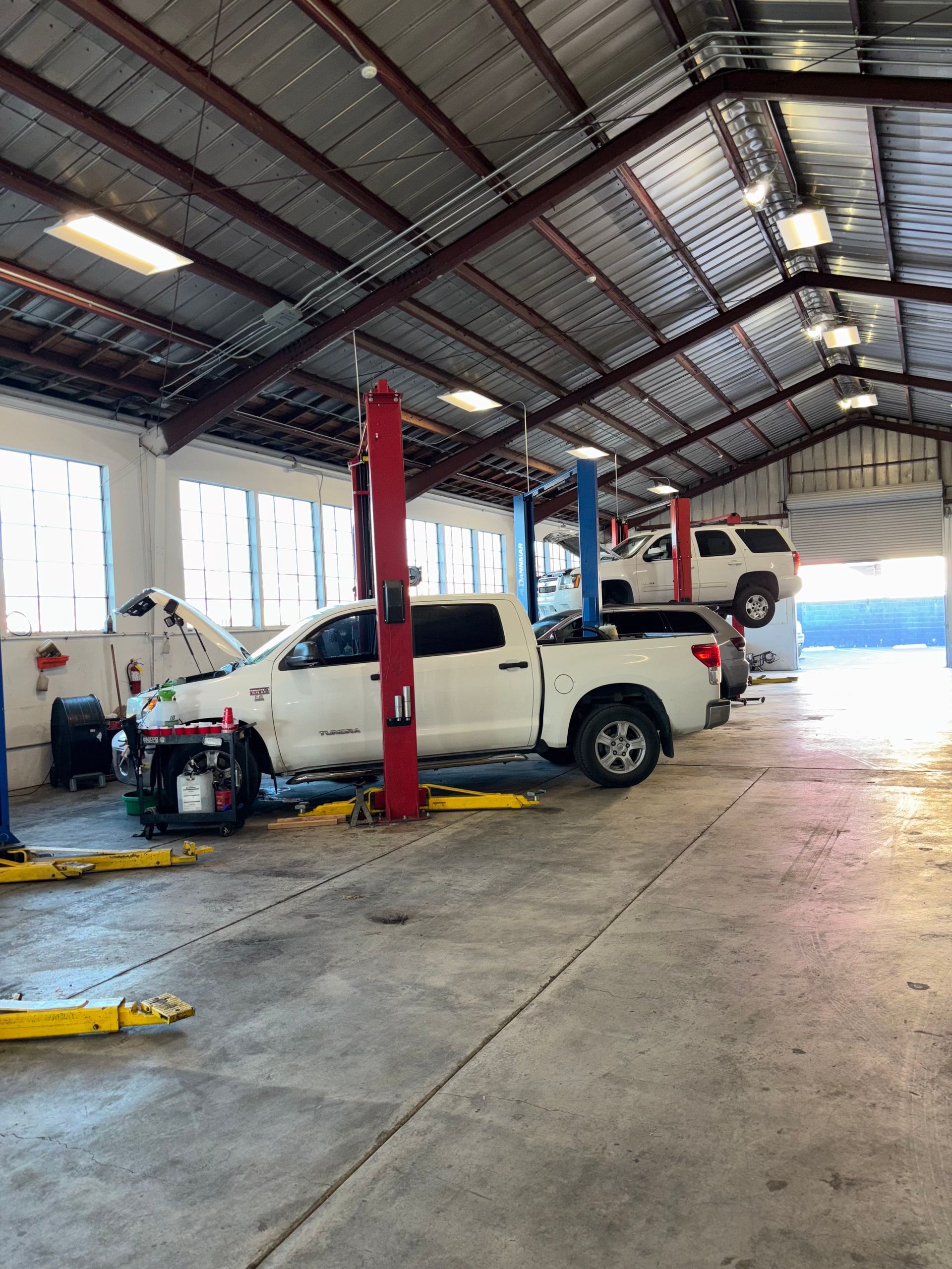 A white truck is on a lift in a garage.